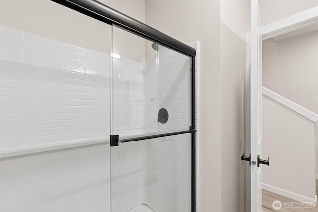 bathroom with a shower stall, baseboards, and wood finished floors