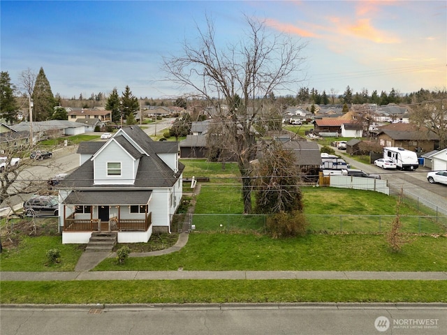 bungalow featuring a fenced front yard, a residential view, a lawn, and a porch