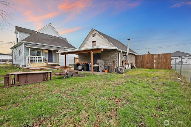 back of property featuring an outbuilding, a yard, and fence