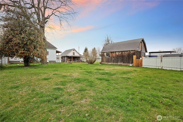 view of yard featuring a barn, fence, and an outbuilding