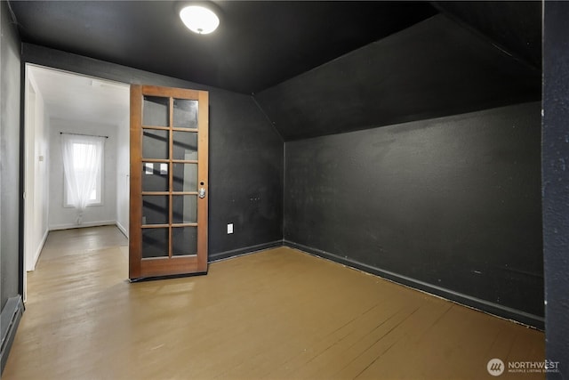 additional living space with baseboards, a baseboard heating unit, lofted ceiling, and wood finished floors