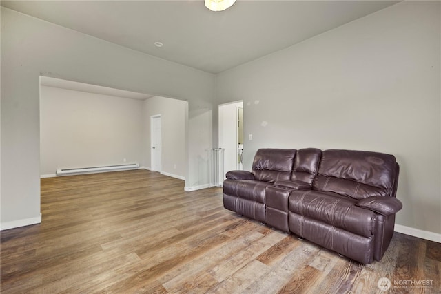 living area featuring a baseboard heating unit, wood finished floors, and baseboards