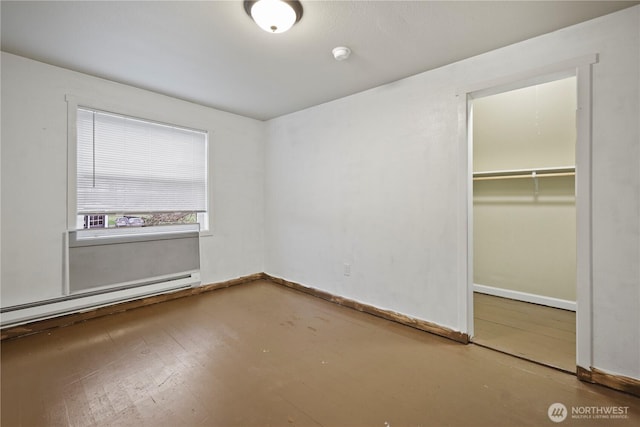 unfurnished bedroom featuring a closet, a spacious closet, baseboards, and a baseboard radiator