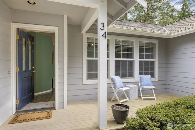 view of exterior entry featuring a porch and a shingled roof