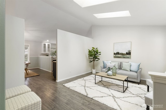 living area with lofted ceiling with skylight, recessed lighting, baseboards, and wood finished floors