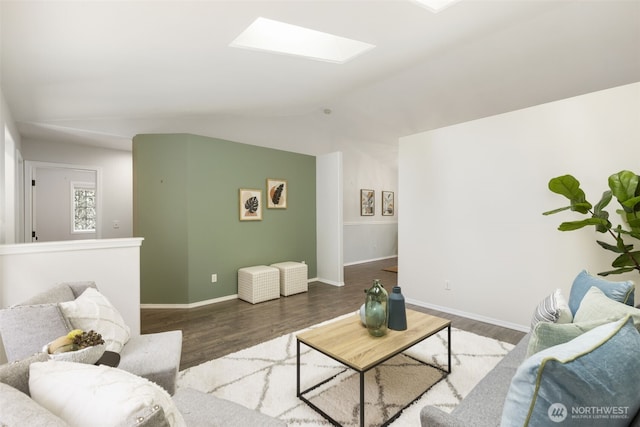 living room with baseboards, vaulted ceiling with skylight, and wood finished floors