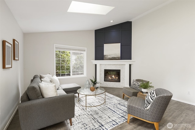 living area with baseboards, lofted ceiling with skylight, recessed lighting, a fireplace, and wood finished floors