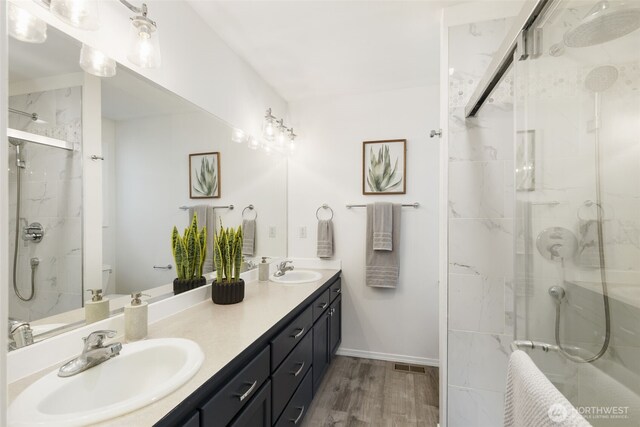 bathroom featuring double vanity, visible vents, a shower stall, and a sink