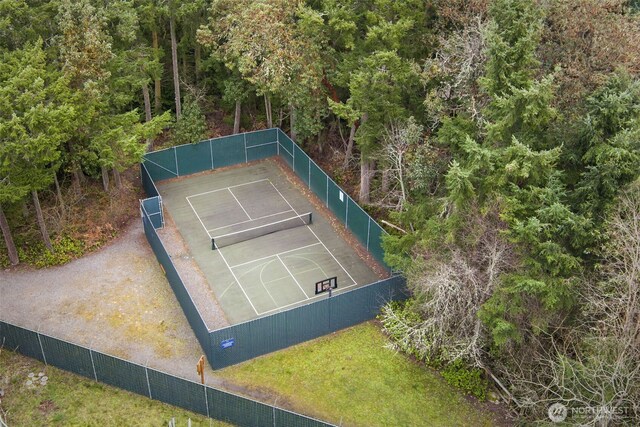 view of tennis court with a yard and fence