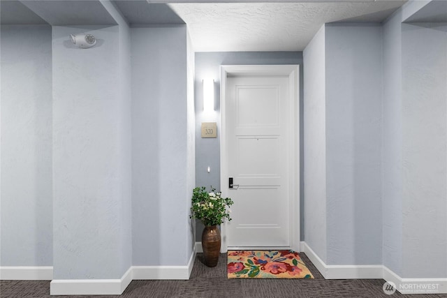 interior space with a textured ceiling, carpet, and baseboards