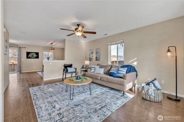 living area with baseboards, ceiling fan, and wood finished floors