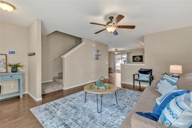 living room with stairs, wood finished floors, a ceiling fan, and baseboards