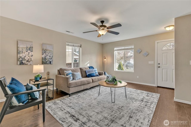 living room with visible vents, a healthy amount of sunlight, dark wood finished floors, and a ceiling fan