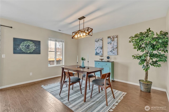 dining area featuring visible vents, an inviting chandelier, baseboards, and wood finished floors