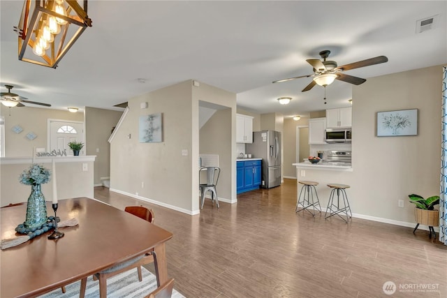 living area featuring wood finished floors, a ceiling fan, visible vents, and baseboards