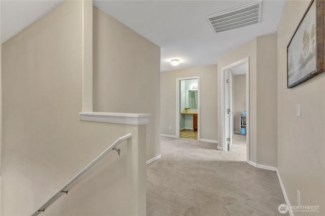 hallway featuring carpet flooring, an upstairs landing, visible vents, and baseboards