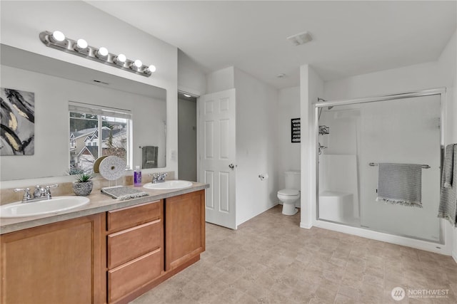 full bath with double vanity, toilet, a stall shower, and a sink