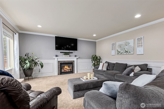 carpeted living room with a wainscoted wall, a glass covered fireplace, and crown molding