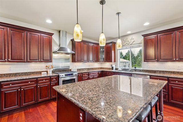 kitchen with dark wood-style floors, dark brown cabinets, appliances with stainless steel finishes, and wall chimney exhaust hood