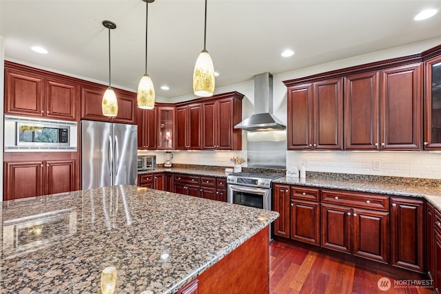 kitchen with dark wood-style floors, dark brown cabinets, glass insert cabinets, appliances with stainless steel finishes, and wall chimney range hood