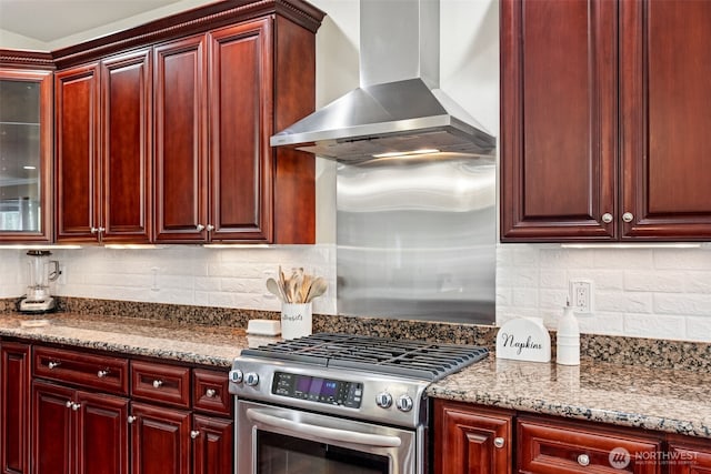 kitchen with decorative backsplash, gas range, reddish brown cabinets, and wall chimney exhaust hood