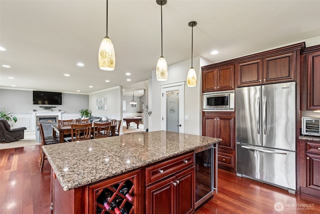 kitchen featuring light stone counters, dark wood-style flooring, a warm lit fireplace, stainless steel appliances, and wine cooler