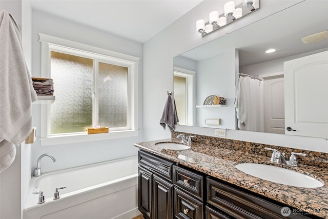 bathroom with double vanity, a garden tub, and a sink