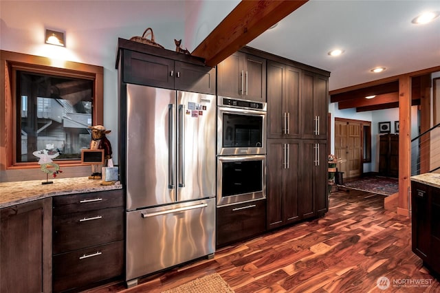 kitchen featuring dark wood-style flooring, dark brown cabinetry, light stone countertops, recessed lighting, and appliances with stainless steel finishes