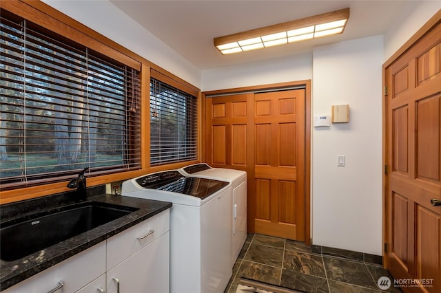 laundry room featuring a sink, cabinet space, independent washer and dryer, and stone finish floor