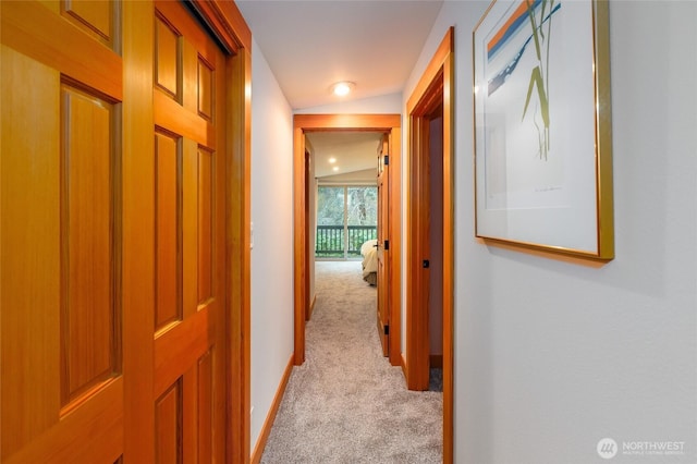 corridor featuring baseboards and light carpet