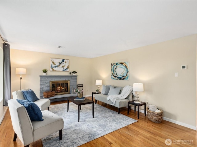 living room featuring visible vents, baseboards, light wood-style flooring, and a fireplace