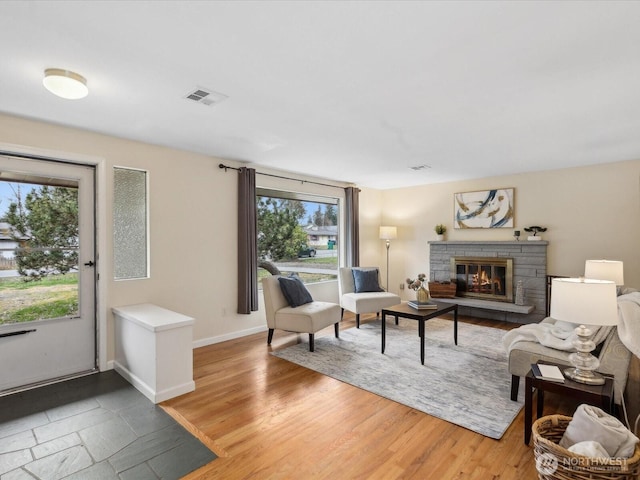 living area featuring light wood finished floors, visible vents, a fireplace, and baseboards