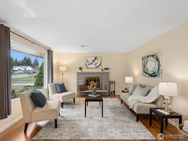 living area featuring visible vents, baseboards, wood finished floors, and a fireplace