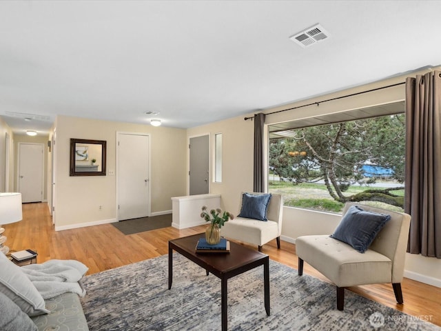 living area featuring light wood finished floors, visible vents, and baseboards