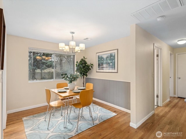 dining area with a notable chandelier, visible vents, baseboards, and wood finished floors