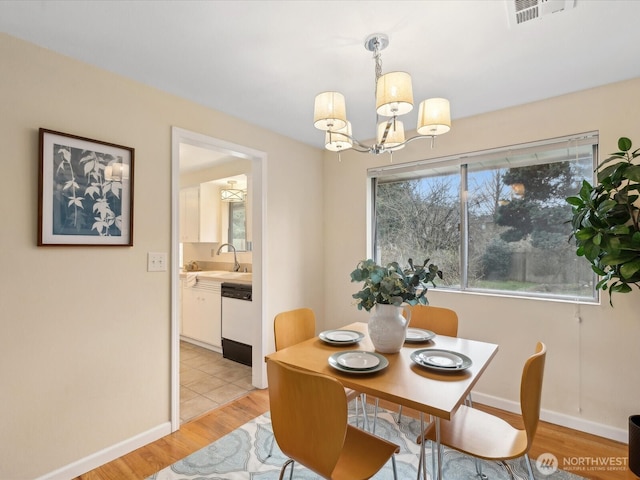 dining space featuring visible vents, baseboards, a notable chandelier, and light wood finished floors