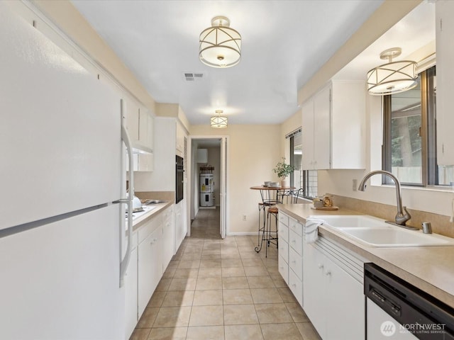 kitchen with white appliances, visible vents, a sink, light countertops, and white cabinetry