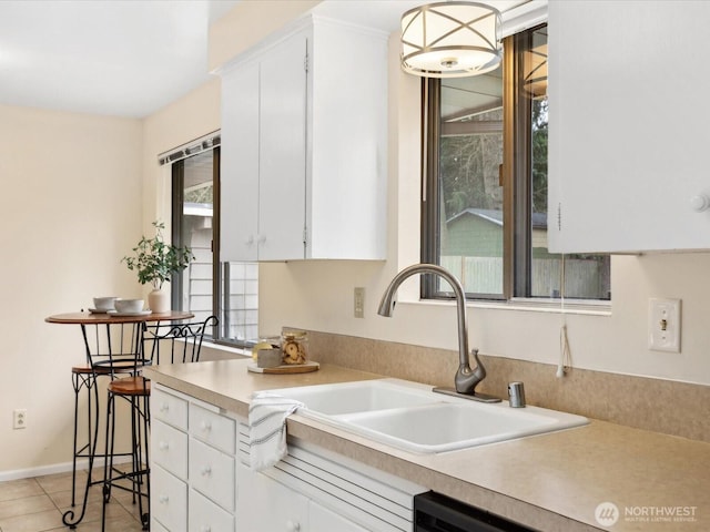 kitchen featuring white cabinetry, light countertops, light tile patterned floors, and a sink