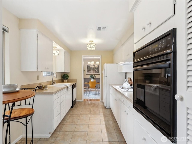 kitchen with white cabinetry, light countertops, visible vents, and a sink