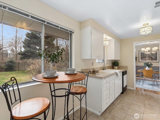 kitchen with visible vents, a sink, white cabinetry, light countertops, and dishwasher