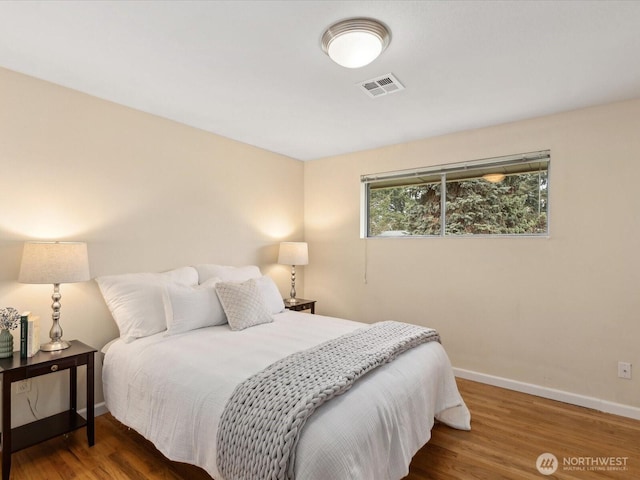 bedroom featuring visible vents, baseboards, and wood finished floors