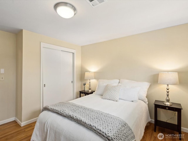 bedroom featuring visible vents, baseboards, a closet, and wood finished floors