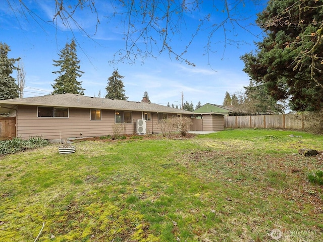 rear view of house with an outbuilding, a lawn, a fenced backyard, and a shed