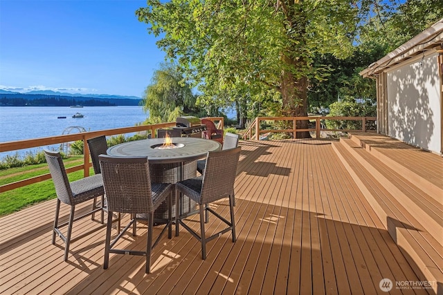 deck featuring an outdoor fire pit and a water view