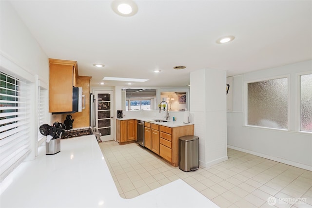 kitchen with recessed lighting, a sink, light countertops, appliances with stainless steel finishes, and brown cabinets