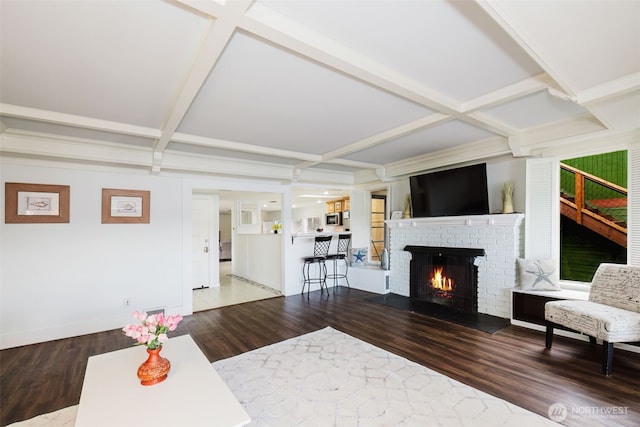 living room with beamed ceiling, coffered ceiling, wood finished floors, a fireplace, and baseboards