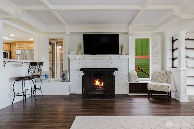 living room with a brick fireplace, coffered ceiling, and wood finished floors