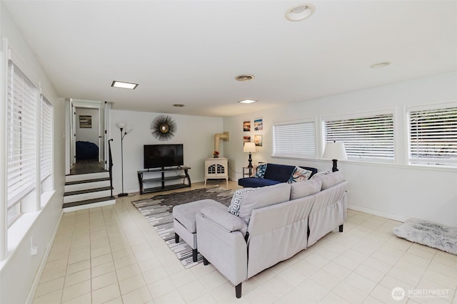 living area featuring light tile patterned floors, baseboards, and a wood stove