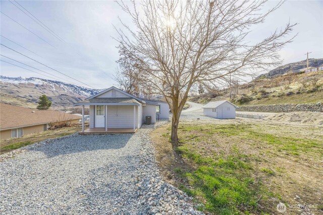 view of front of property featuring a mountain view, central AC, and an outdoor structure