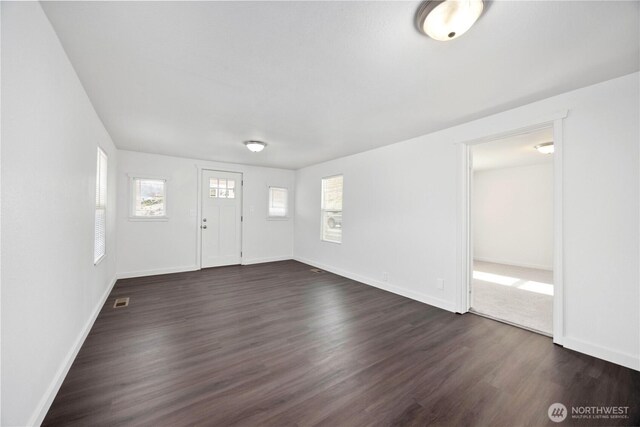 entryway with dark wood-type flooring, baseboards, and visible vents